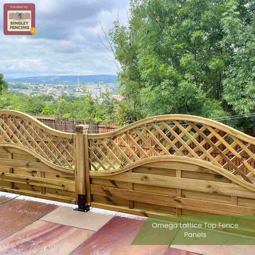 A KDM Omega Lattice Top Fence Panel (OLT) with a curved lattice design is installed on a patio, overlooking trees and a distant town under a cloudy sky. Text reads: Omega Lattice Top Fence Panels by KDM.