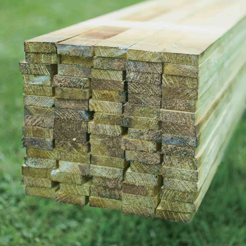 A close-up of stacked rectangular KDM Fence Panel Extension Kits with rough edges, resting on green grass outdoors—ideal for enhancing fencing systems in West Yorkshire.