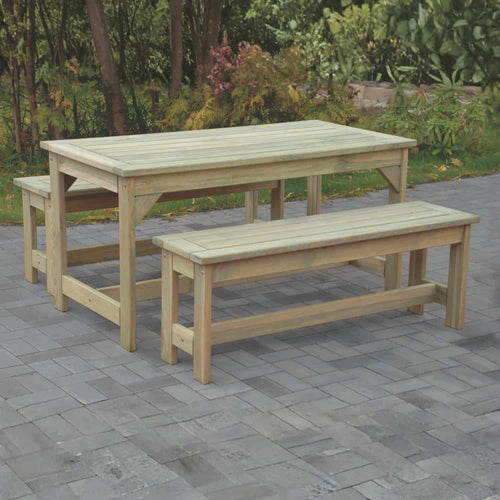 The KDM Patio Dining Set - PDS includes a wooden picnic table and two matching benches, set on a paved patio with lush green plants and trees in the background.