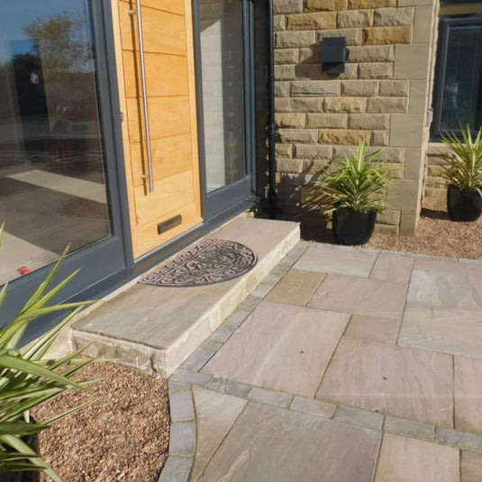 Front entrance of a house with a stone pathway and wooden door.