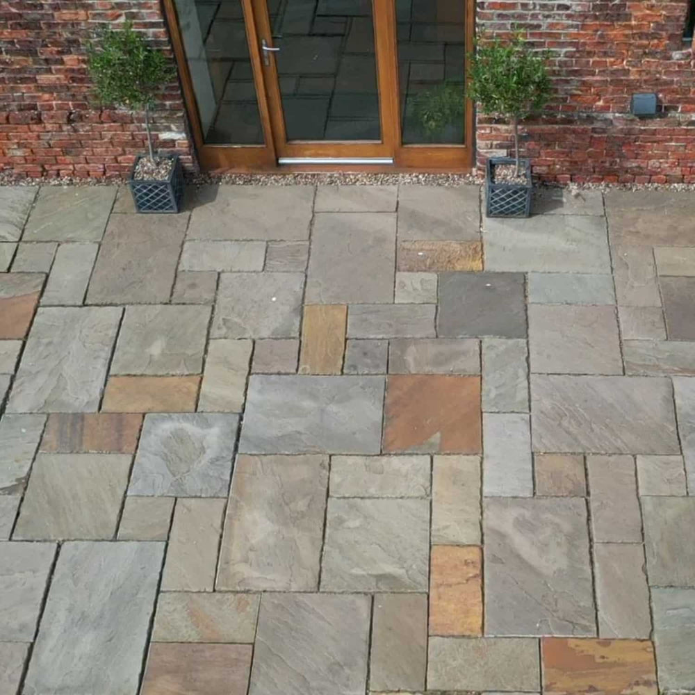 Paved patio area with a brick wall and glass door in the background