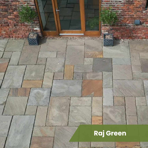 A patio with rectangular and square Bingley Fencing Indian Sandstone Paving Project Pack in shades of gray, tan, and brown, set by a brick wall with glass doors and two potted plants. "Raj Green" appears at the bottom right.