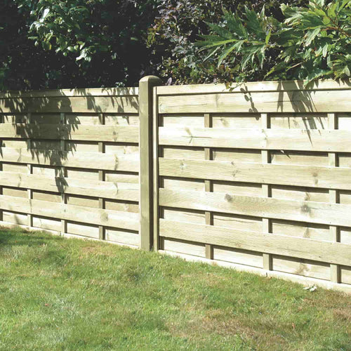 A light wooden fence made of KDM Square Horizontal Fence Panels (SH) stands on a grassy lawn, with green bushes and trees in the background.