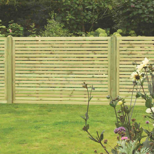 The KDM Slatted Fence Panels feature a contemporary design that enhances the gardens privacy and security, while vibrant green grass and colorful flowers complement leafy shrubs, creating a picturesque backdrop.