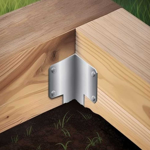 The John George Internal Corner Support Spike for Sleepers securely joins two wooden beams at a right angle above soil and grass, reinforcing outdoor corners with strong galvanised steel and screws.