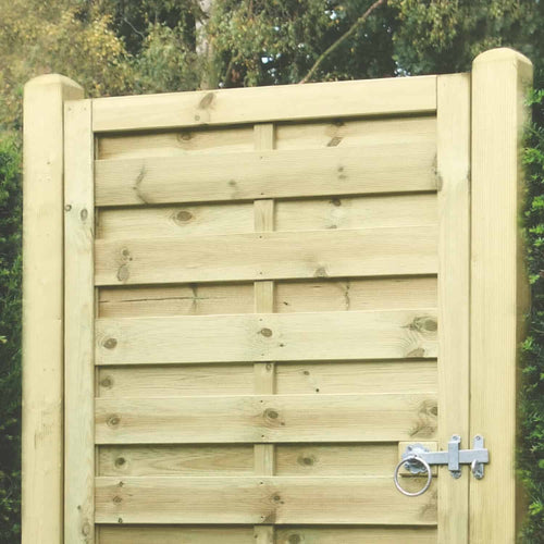 A close-up of a wooden garden gate with horizontal slats and metal latch, framed by KDM Smooth planed European Gate Posts (100mm x 100mm PAR), surrounded by greenery and trees in the background.