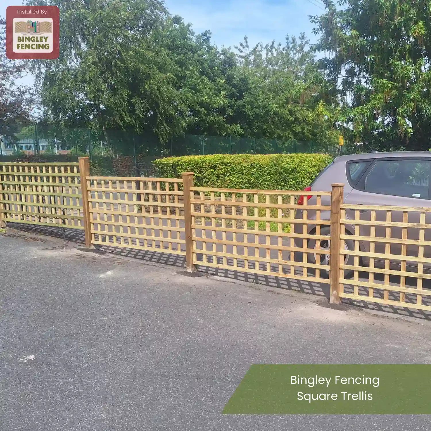 A wooden square trellis fence installed beside a parked car on a paved surface, with trees, a hedge, and a sports court in the background. Text reads Bingley Fencing Square Trellis.