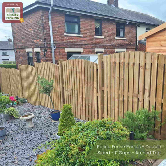 Bingley Fencing’s Paling Fence Panels - Double Sided with 1 gaps and an arched top separate a garden of plants and gravel from a brick house and shed, with a birdbath and potted plants in the foreground.