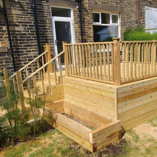 raised wooden decking area with vertical spindles and wooden steps. Also a raised wooden planter