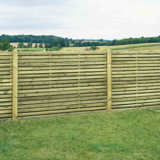 The KDM Double Sided Slatted Panels (SDS180) are shown installed on green grass, with countryside hills and trees in the background beneath a cloudy sky.