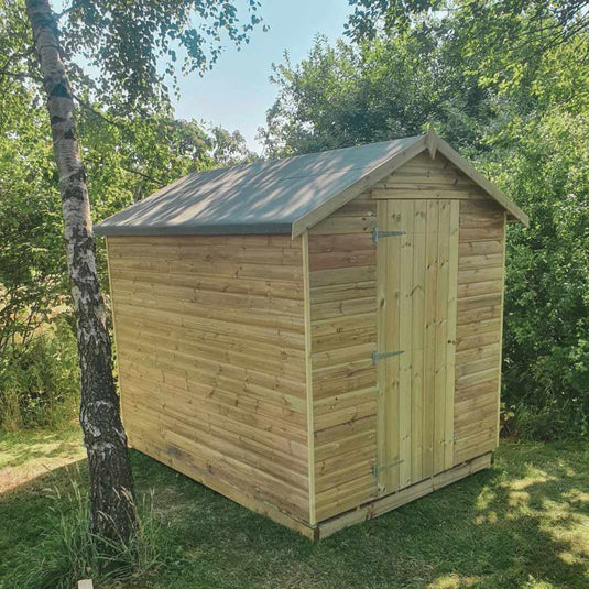 A wooden garden shed with single door at one end and apex style pitched roof. Installed in a garden with grass and lots of trees,