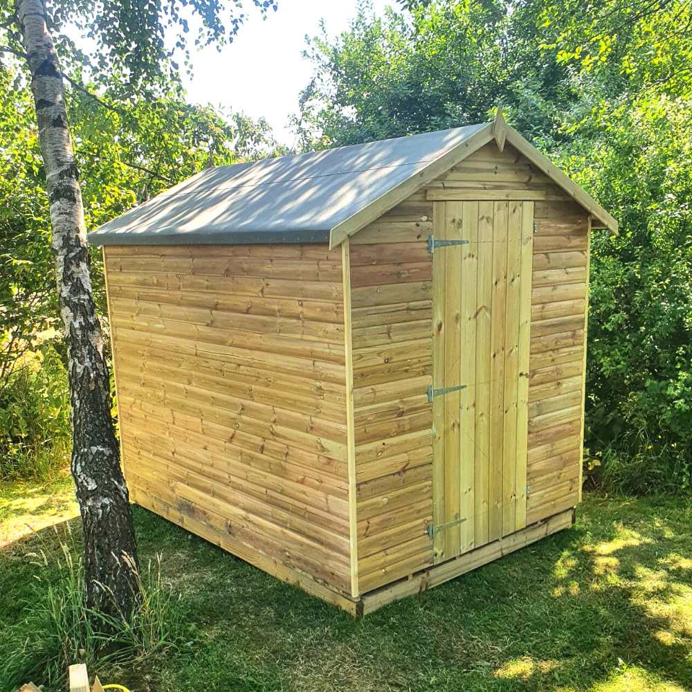 Wooden shed with apex roof installed on a timber base installed in a garden surrounded by trees