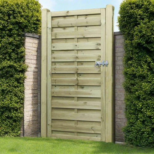 A tall KDM Square Horizontal Euro-Gate, crafted from horizontal planks, stands between two brick walls. This decorative timber gate features a metal latch and is flanked by lush green hedges, with grass in the foreground.