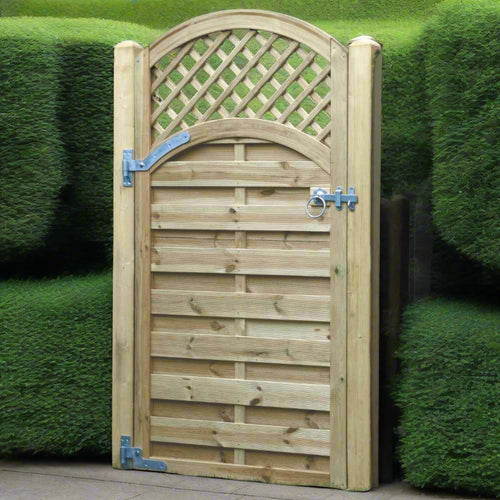 The KDM Arched Lattice Top Euro-Gate, featuring horizontal slats and secured with metal hinges and a latch, seamlessly blends into the lush green hedges.