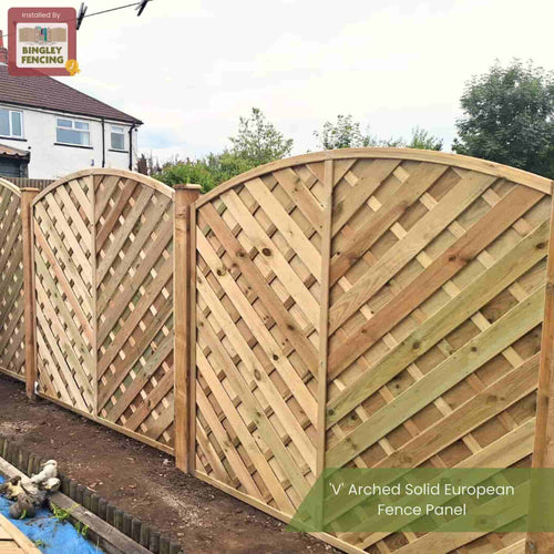 KDM 'V' Arched Solid Fence Panel - VA, featuring a diagonal lattice design, is installed as a privacy fence along the garden boundary, with a house and trees visible in the background.