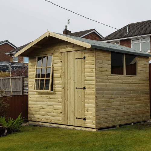 A Bingley Fencing Country Cabin Shed with a sloped roof is positioned on a well-maintained lawn in the backyard. It features elegant Georgian windows flanking the front door and boasts loglap cladding for added charm. Several houses can be seen in the background.